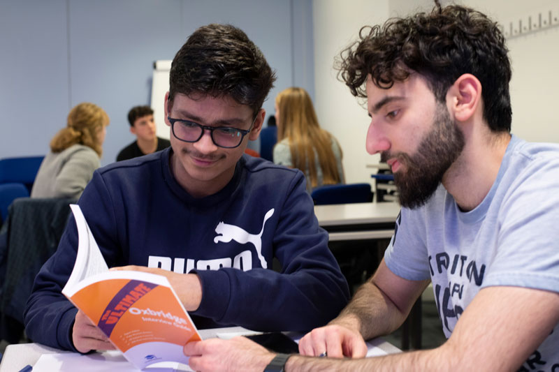 Smiling tutor and student looking in a book together